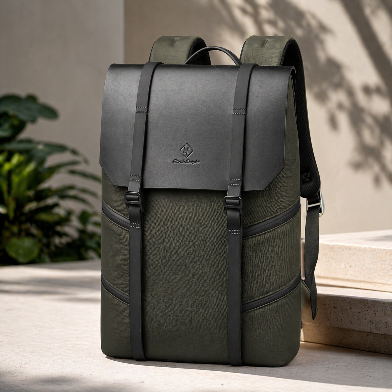 Green backpack with black straps on a light surface with plants in the background