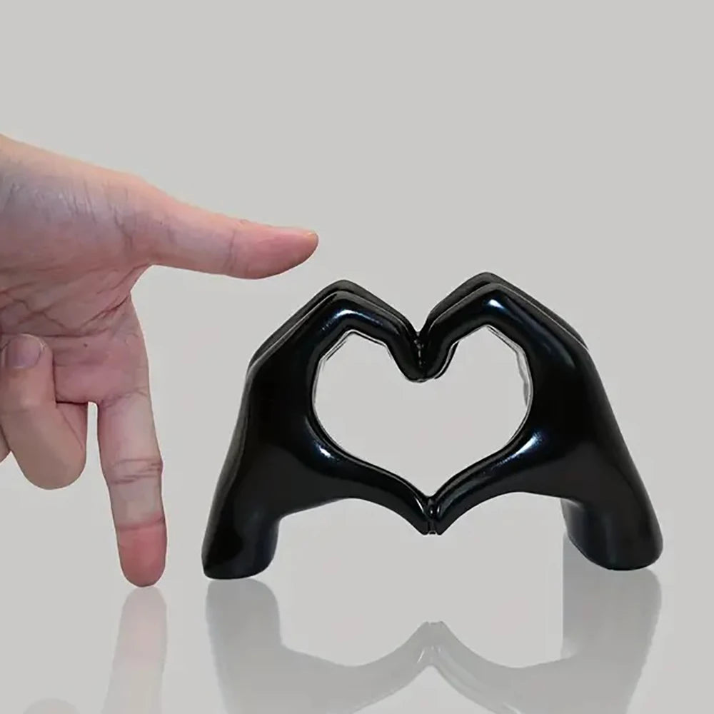 Black heart-shaped object with a hand pointing at it on a gray background