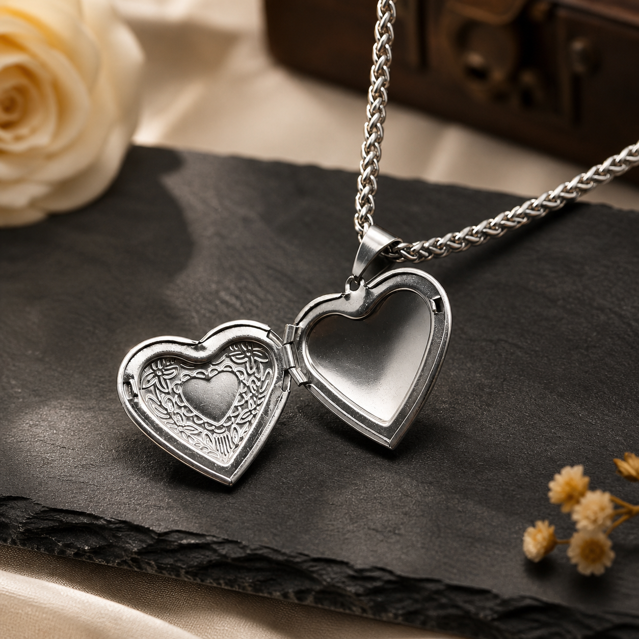 Silver heart-shaped locket on a dark surface with flowers in the background