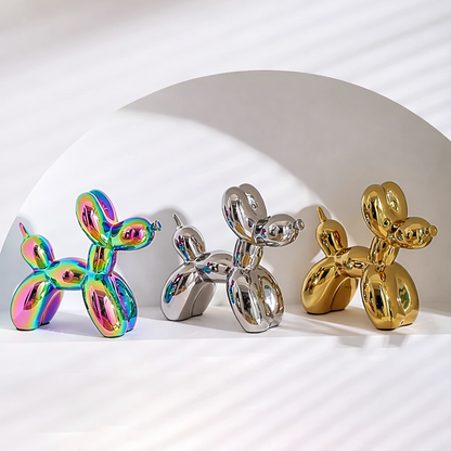 Three metallic dog sculptures in rainbow, silver, and gold on a white background