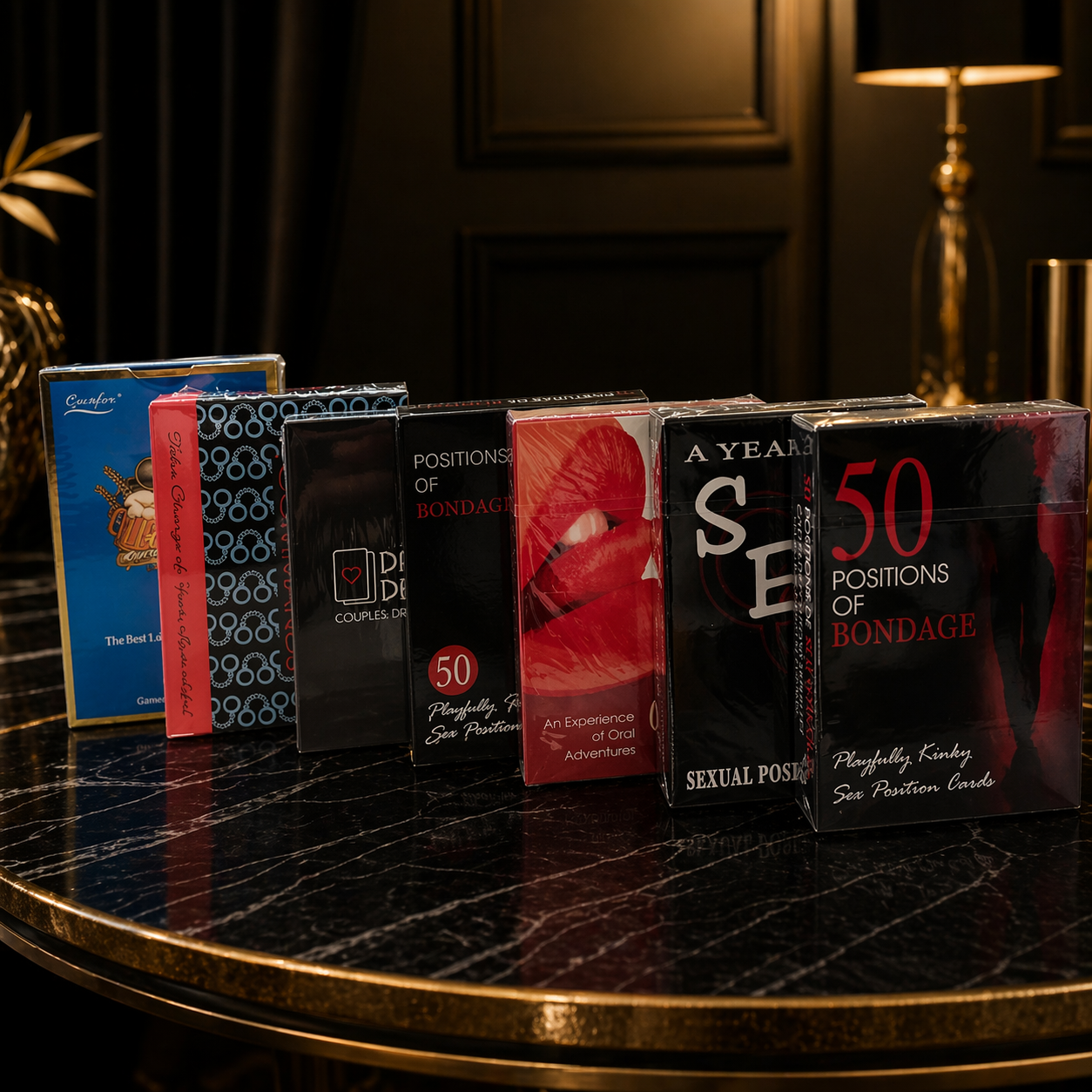 Collection of adult-themed books and cards on a dark surface with a lamp in the background.