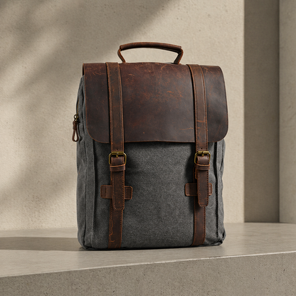 Gray backpack with brown leather straps on a neutral background