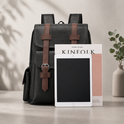 Black backpack with brown straps and a tablet on a neutral background