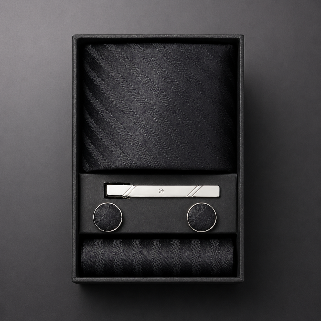 Black tie set with silver tie clip in a black box on a dark gray background