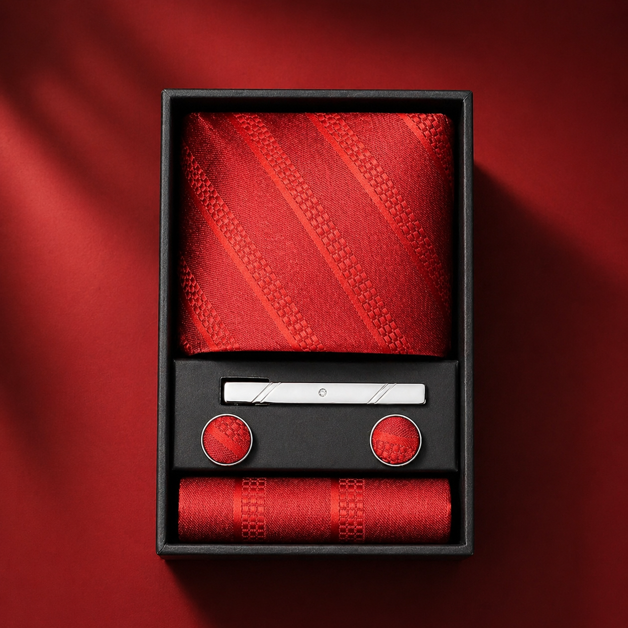 Red tie set with tie, pocket square, and cufflinks in a black box on a red background