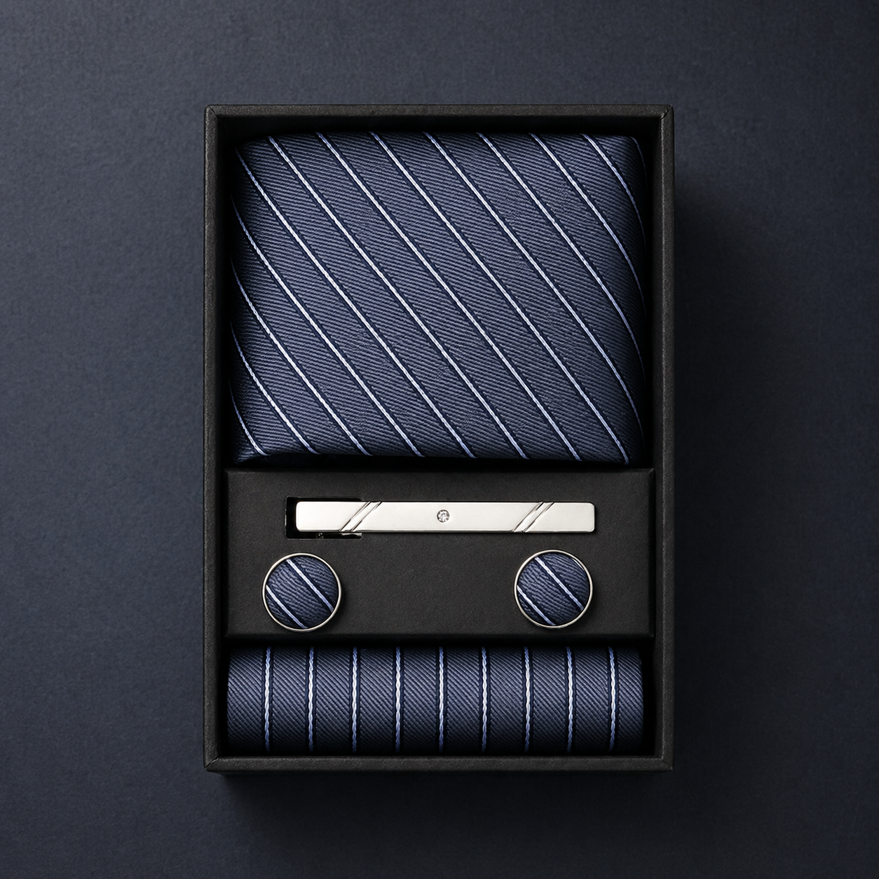 Navy striped tie set with tie clip and pocket square in a black box on a dark background