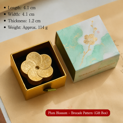 Gold plum blossom-shaped object in a gift box with product details on a beige background