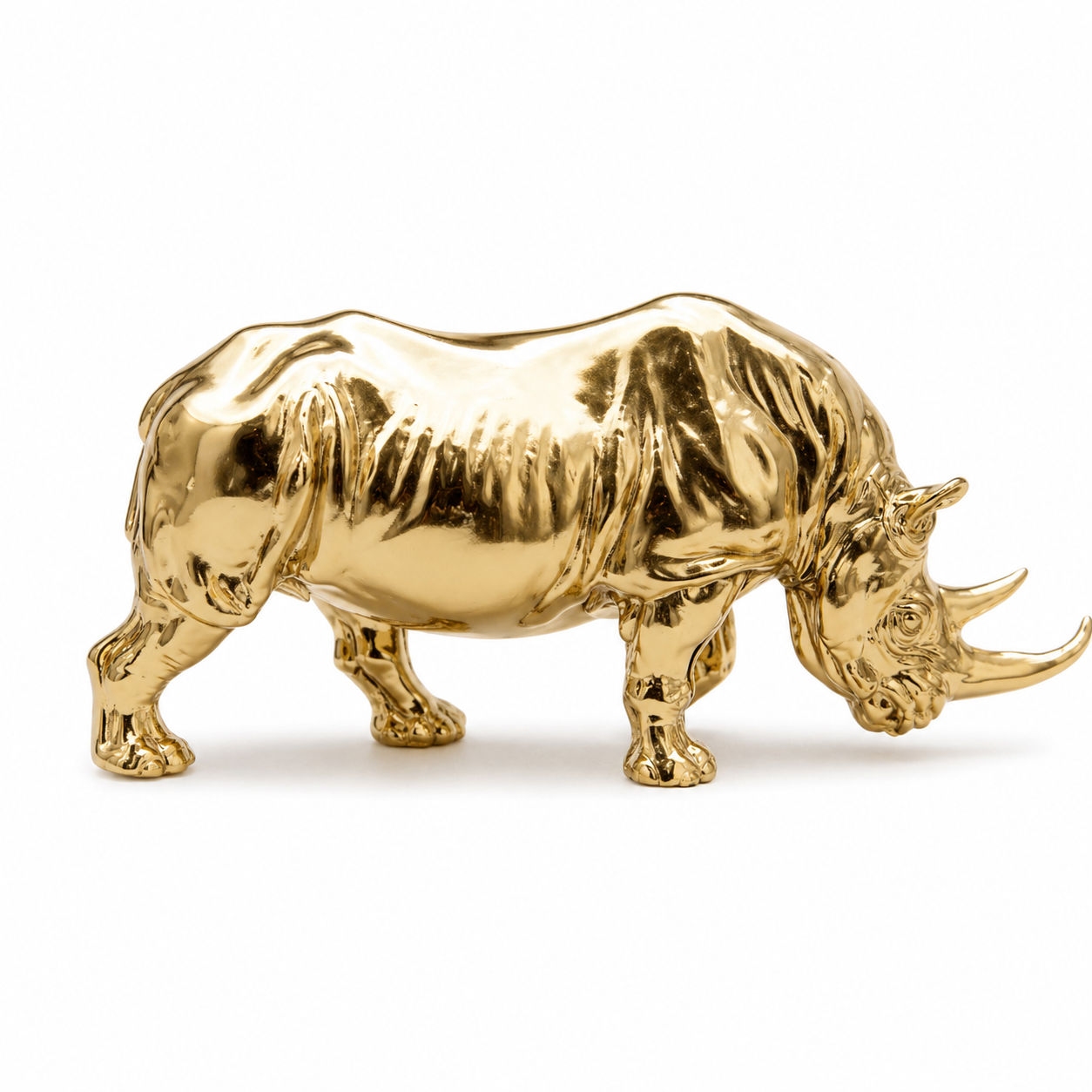 Gold rhinoceros figurine on a white background