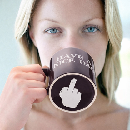 Person holding a mug with 'Have a nice day' and middle finger symbol