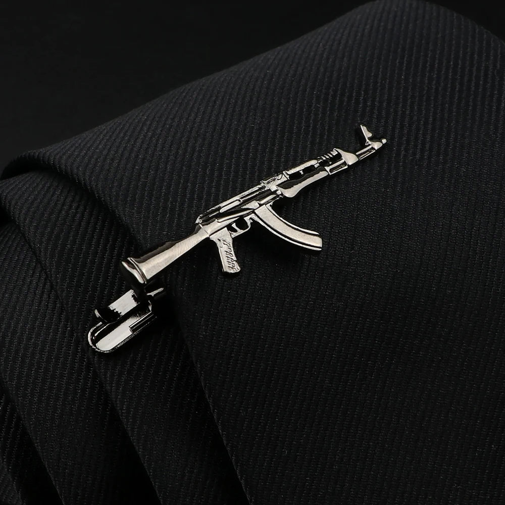 Metallic rifle-shaped tie clip on a black suit jacket