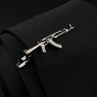 Metallic rifle-shaped tie clip on a black suit jacket