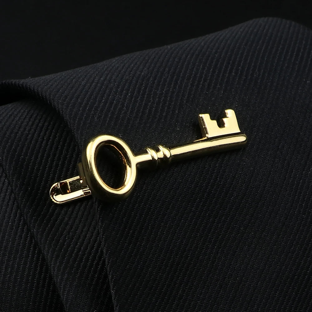 Gold key-shaped cufflink on a black fabric background