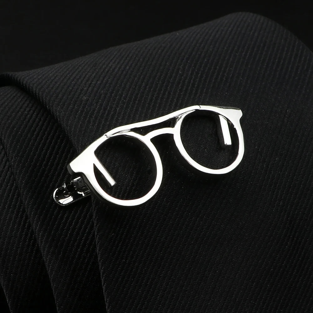 Silver eyeglasses-shaped lapel pin on a black textured fabric background