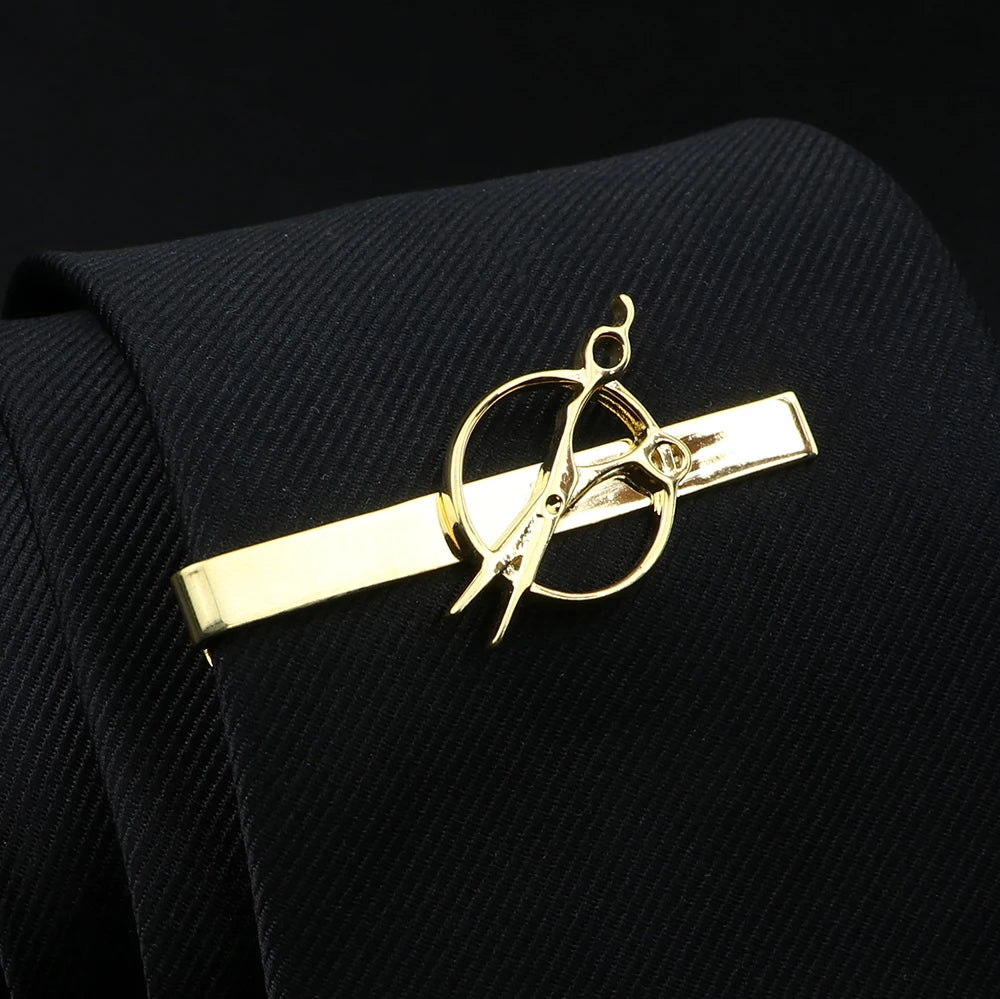Gold tie clip with scissors design on a black tie against a black background