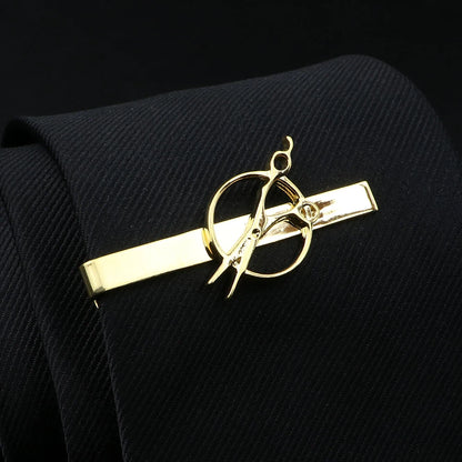 Gold tie clip with scissors design on a black tie against a black background