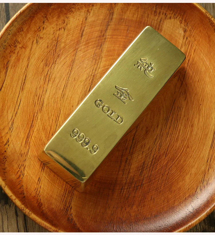 Gold bar with 'GOLD' and '999.9' marking on a wooden surface