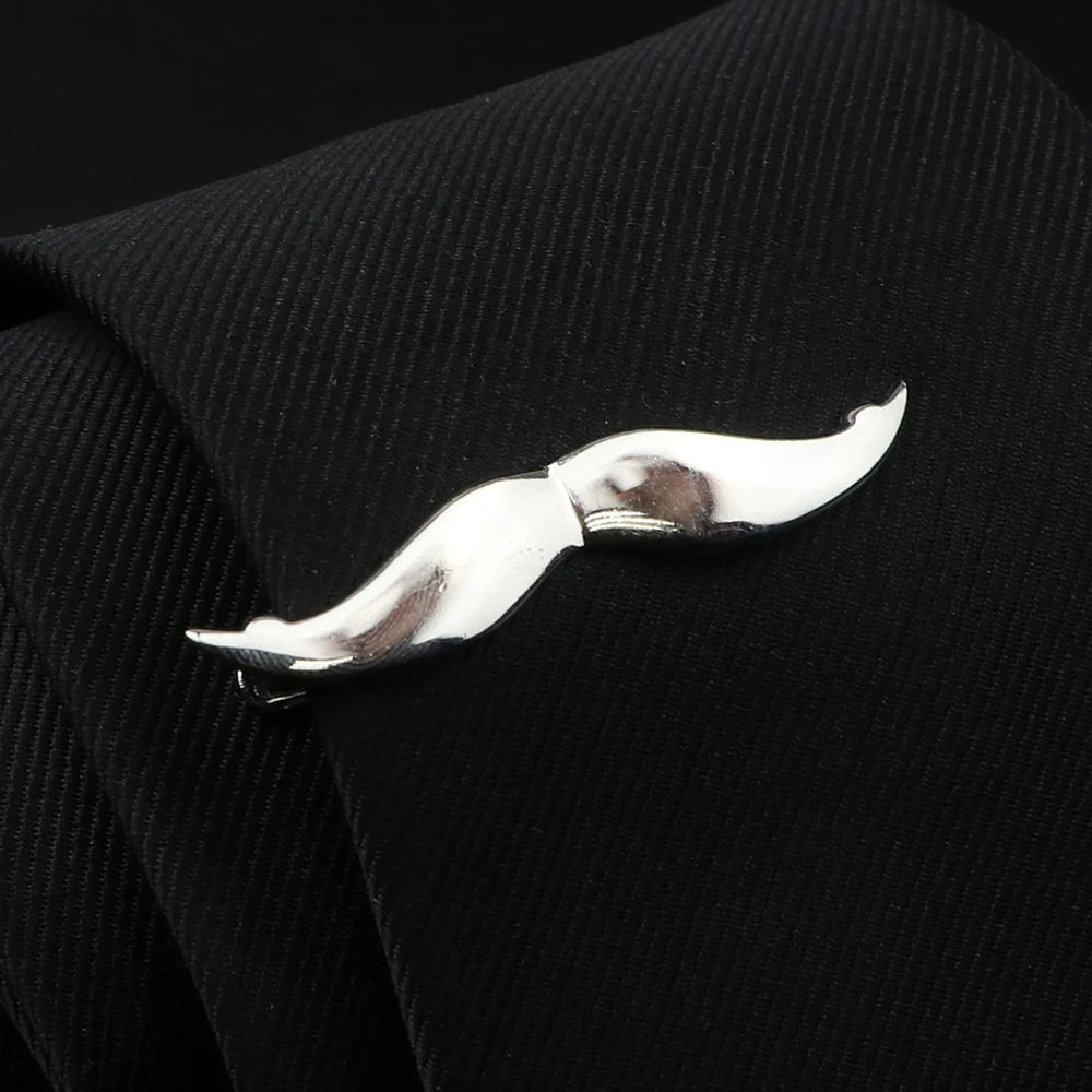 Silver mustache-shaped tie clip on a black textured tie.