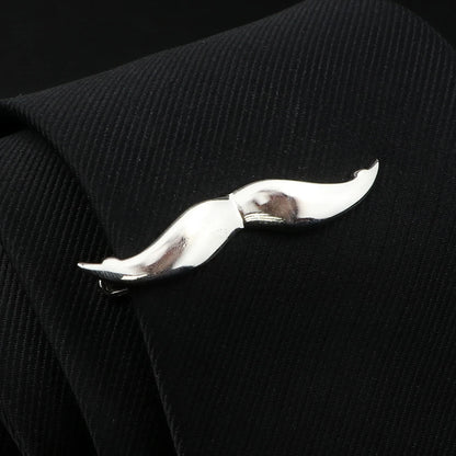 Silver mustache-shaped tie clip on a black textured tie.