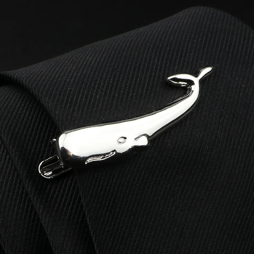 Metallic whale-shaped tie clip on a black suit background
