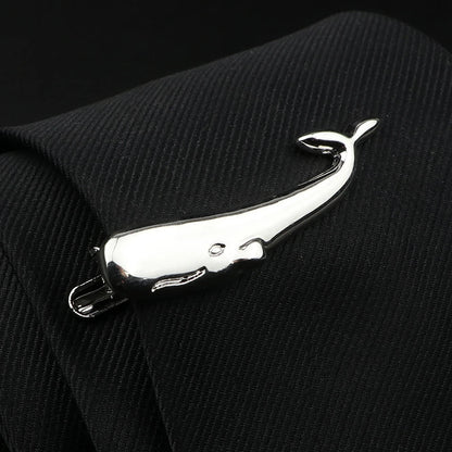 Metallic whale-shaped tie clip on a black suit background