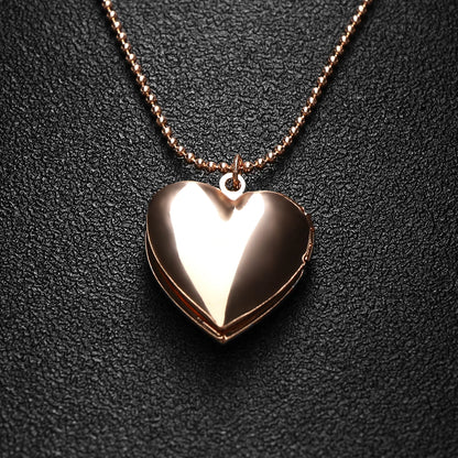 Rose gold heart-shaped locket on a chain against a dark background