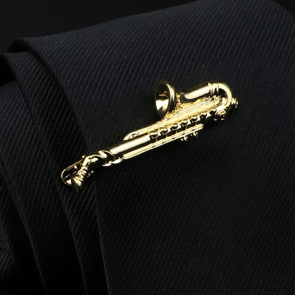 Gold saxophone-shaped tie clip on a black textured fabric background