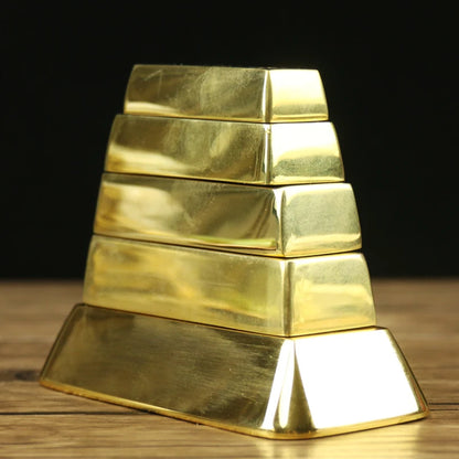 Stack of gold bars arranged in a pyramid shape on a wooden surface with a dark background