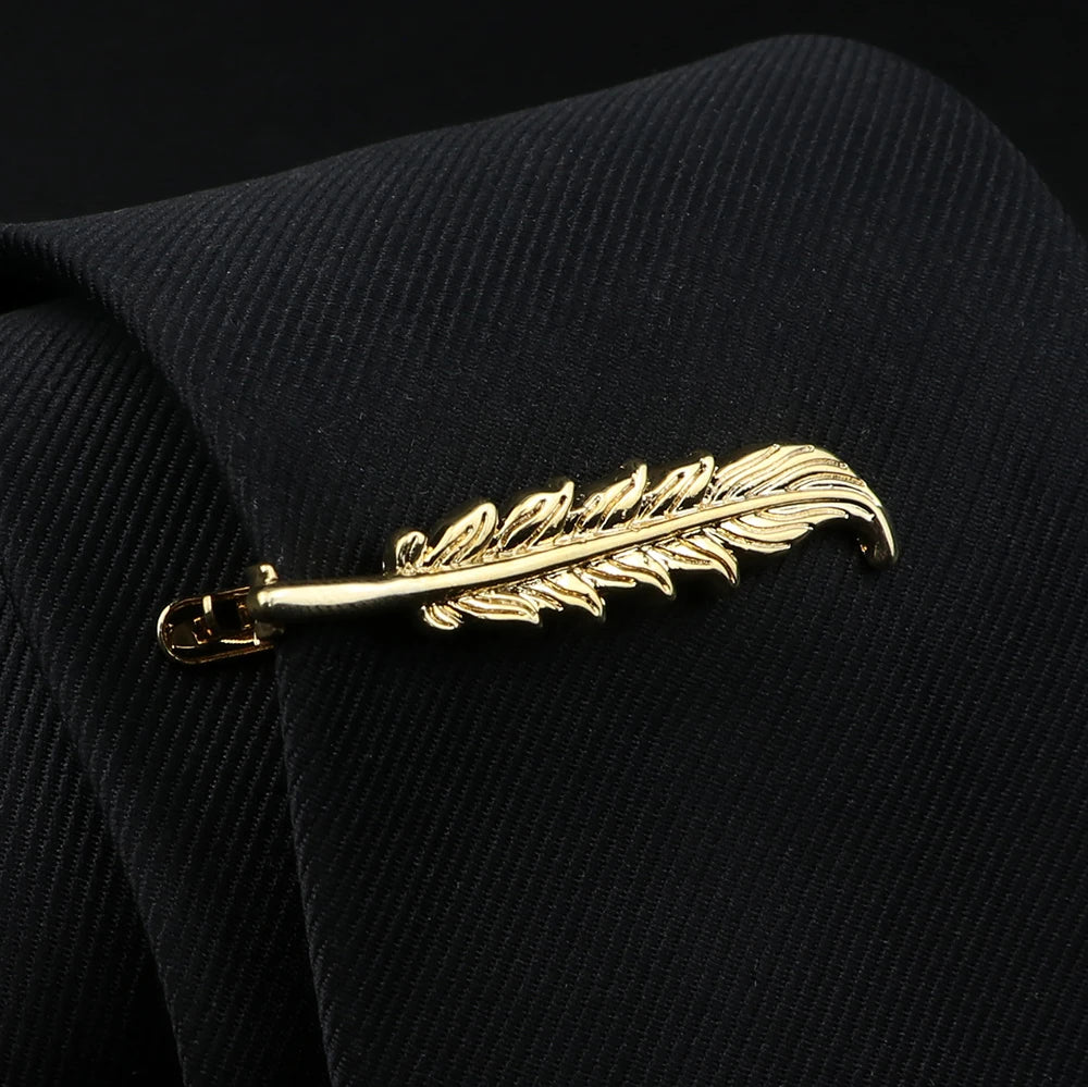 Gold feather-shaped brooch on a black textured fabric background