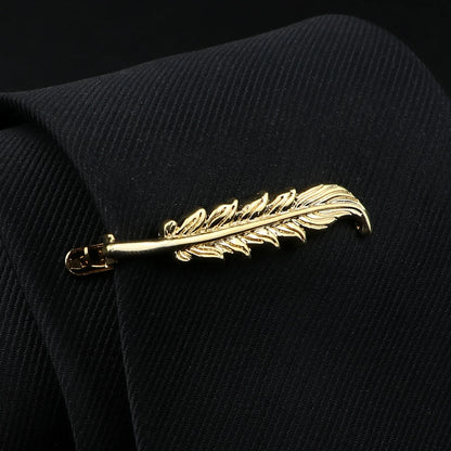 Gold feather-shaped brooch on a black textured fabric background