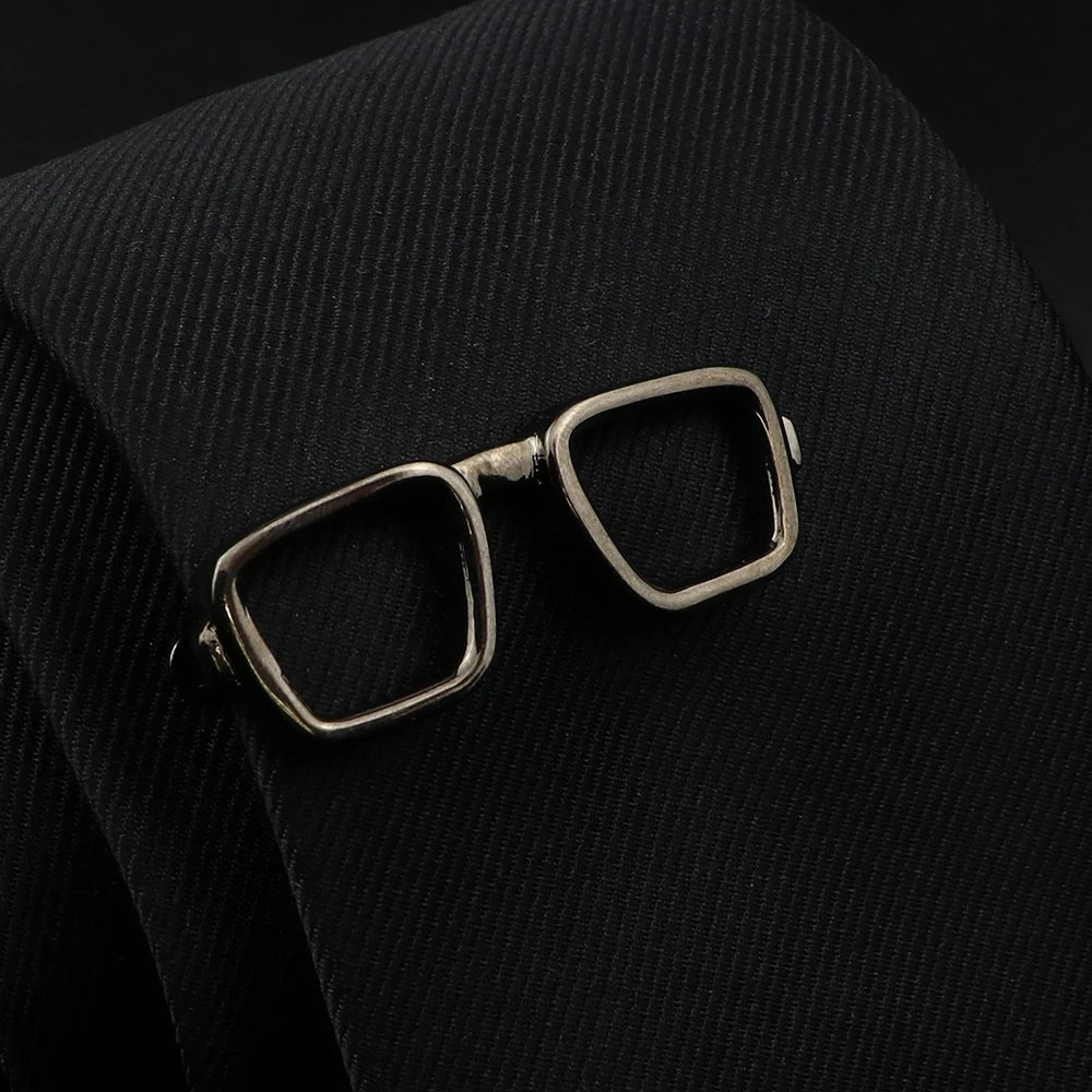 Bronze eyeglasses brooch on a black textured fabric background