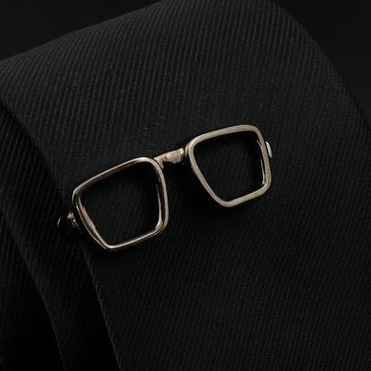 Bronze eyeglasses brooch on a black textured fabric background