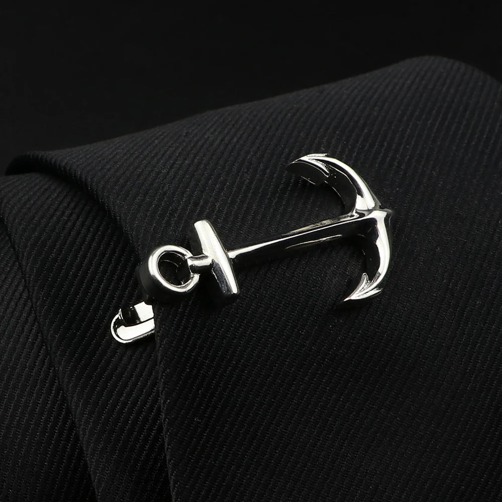 Silver anchor-shaped cufflink on a black textured fabric background