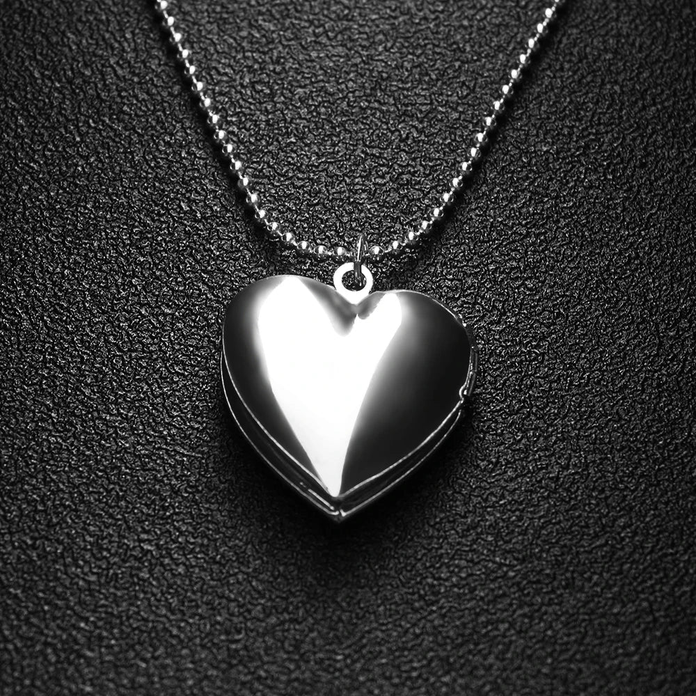Heart-shaped silver locket on a chain against a black textured background