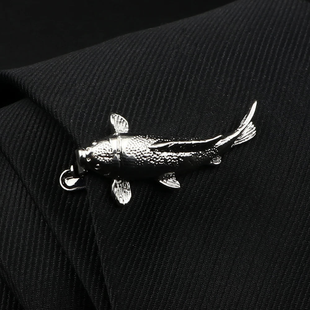 Silver fish-shaped brooch on a black textured fabric background