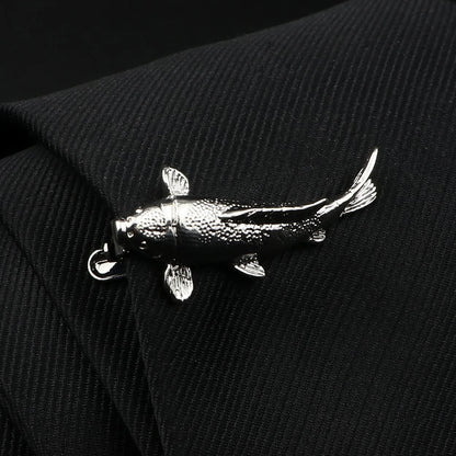 Silver fish-shaped brooch on a black textured fabric background