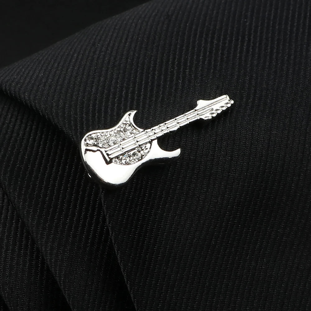 Silver guitar-shaped pin on a black textured fabric background