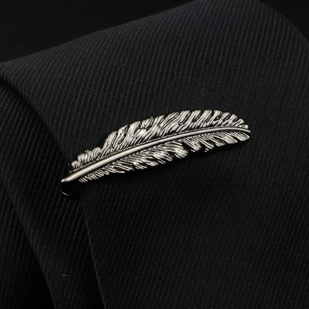 Silver feather-shaped lapel pin on a black suit jacket