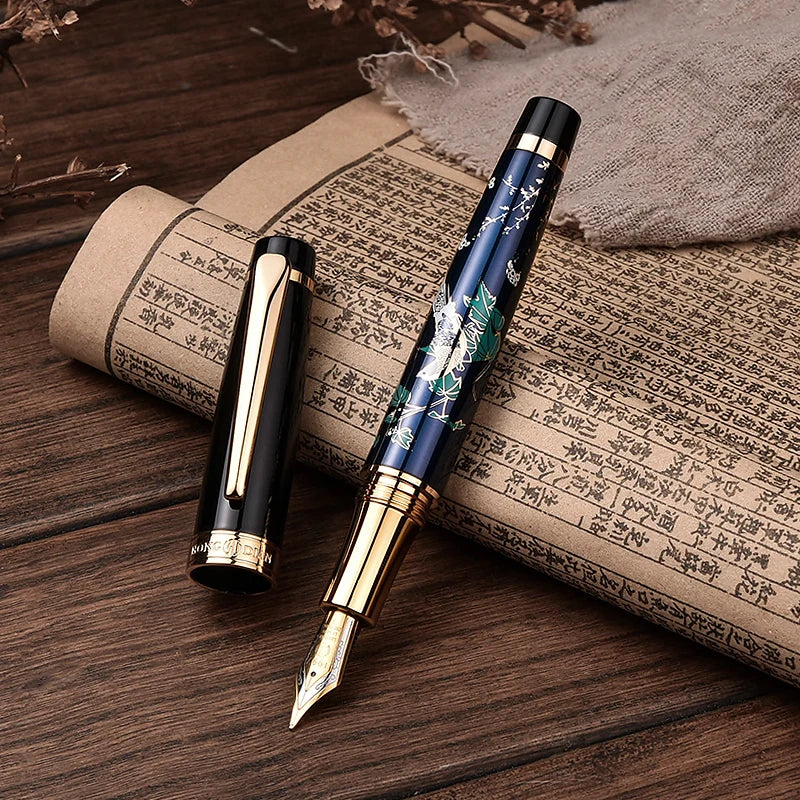 Two fountain pens on a wooden surface with an old book