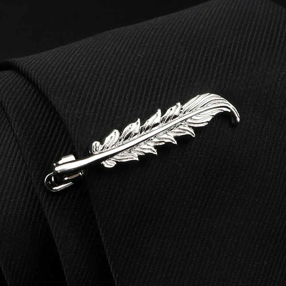 Silver feather-shaped brooch on a black textured fabric background