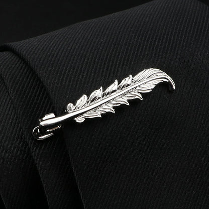 Silver feather-shaped brooch on a black textured fabric background