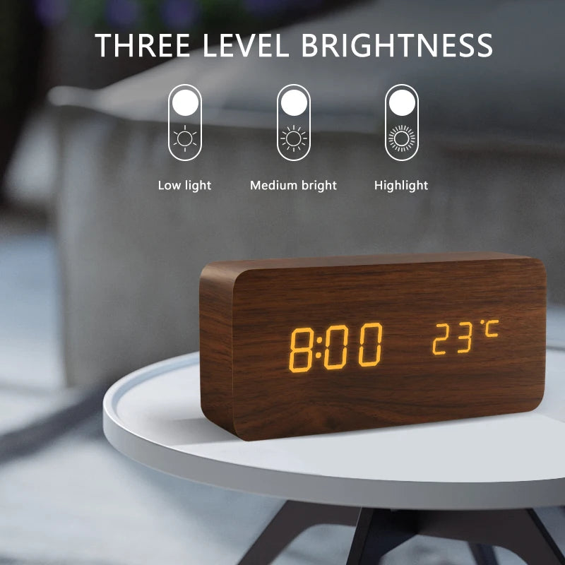 Wooden digital clock with LED display on a table, showing time and temperature, with three level brightness indicators above.