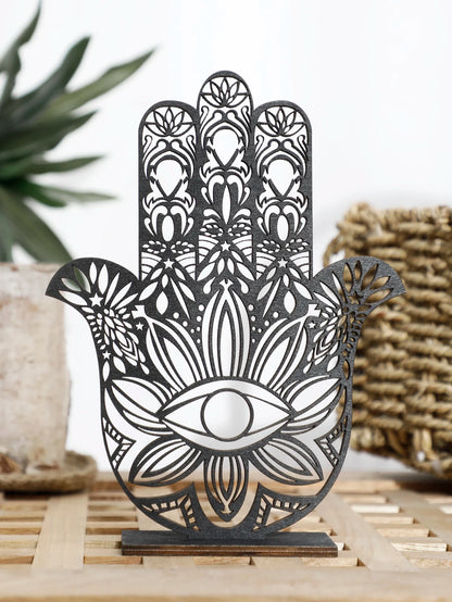 Decorative metal Hamsa hand with intricate patterns on a wooden stand.