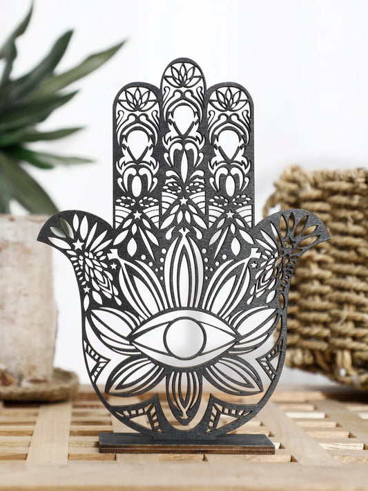 Decorative metal Hamsa hand with intricate patterns on a wooden stand.