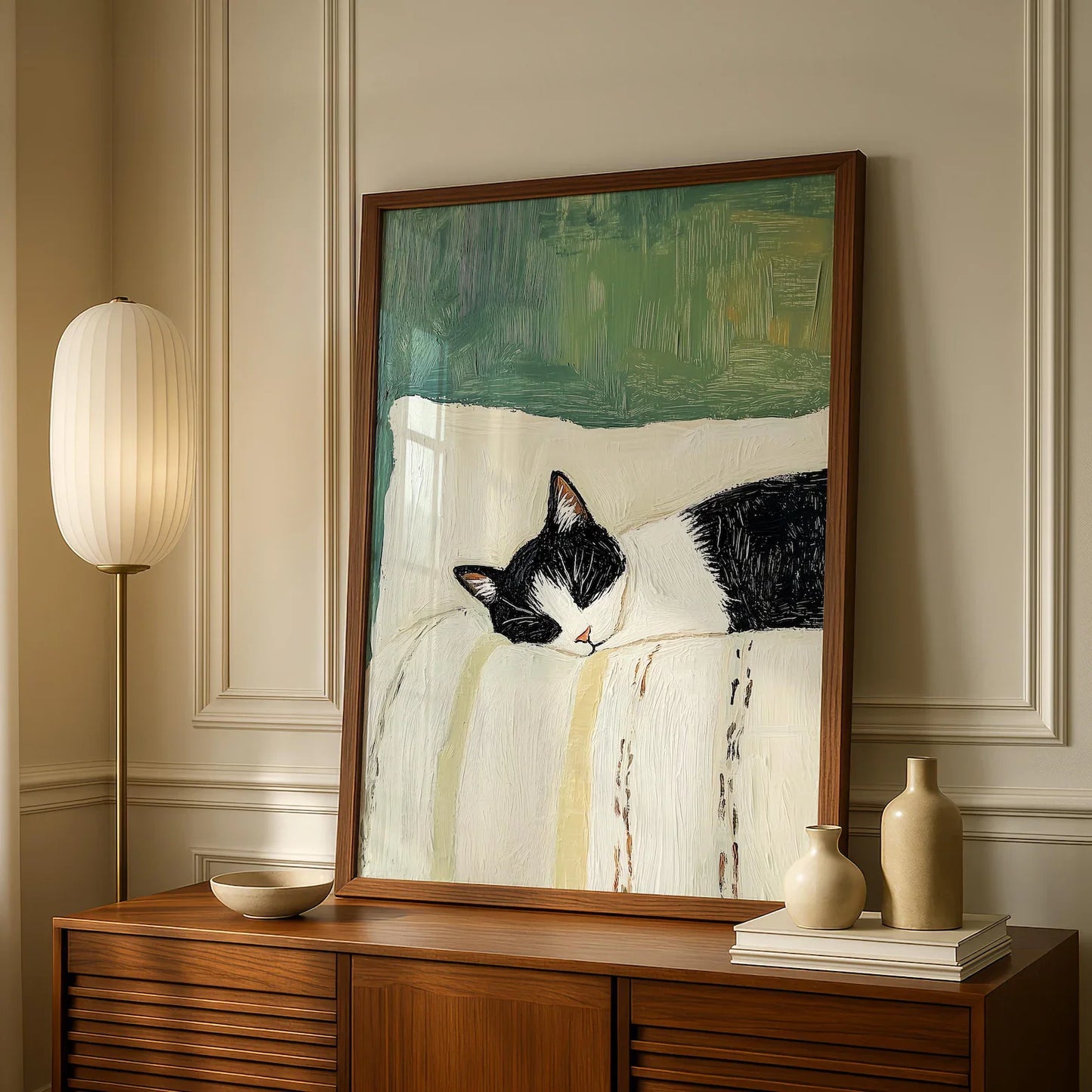 Framed painting of a black and white cat on a wall above a wooden cabinet.