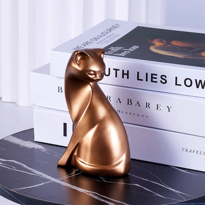 Bronze cat figurine on a marble surface with books in the background