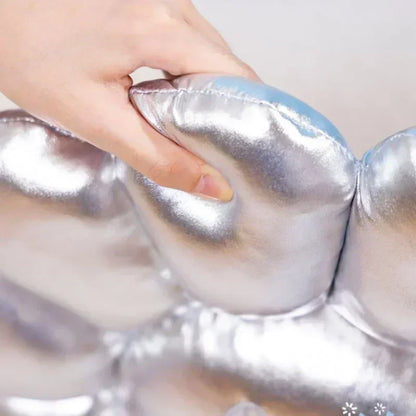 Silver inflatable ring with a hand touching it against a light background