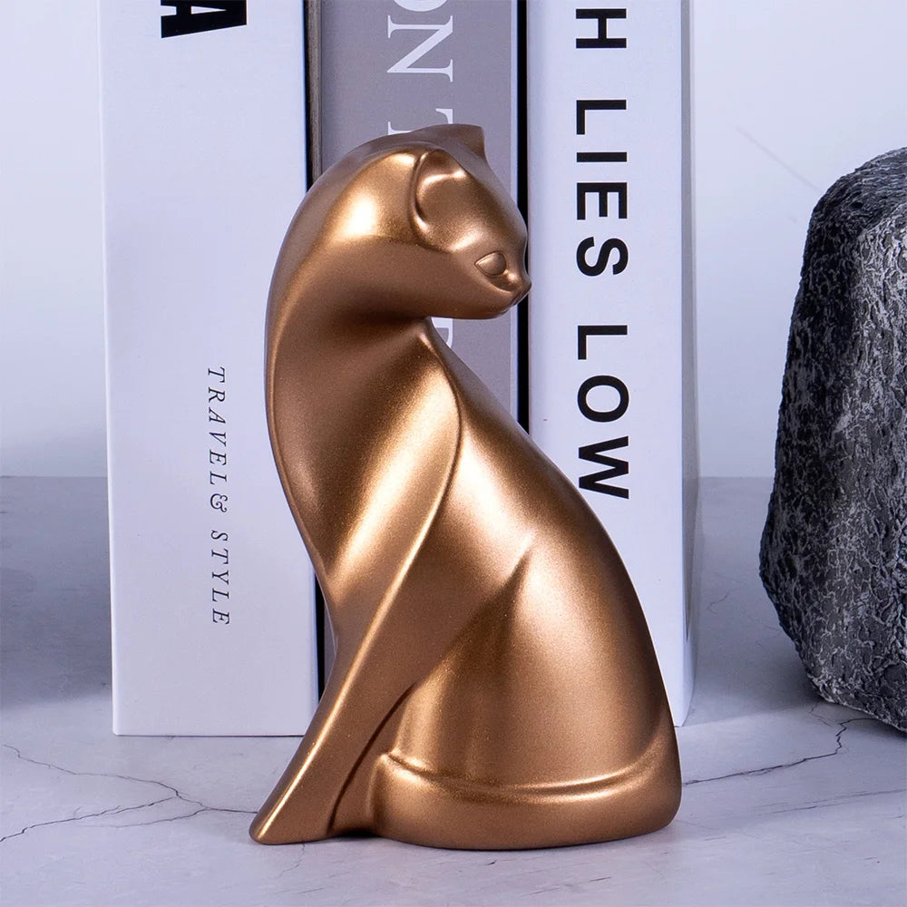 Gold cat-shaped object on a surface with books in the background
