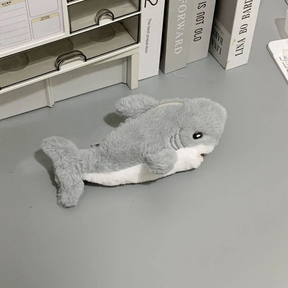 Plush shark toy on a gray floor with books in the background