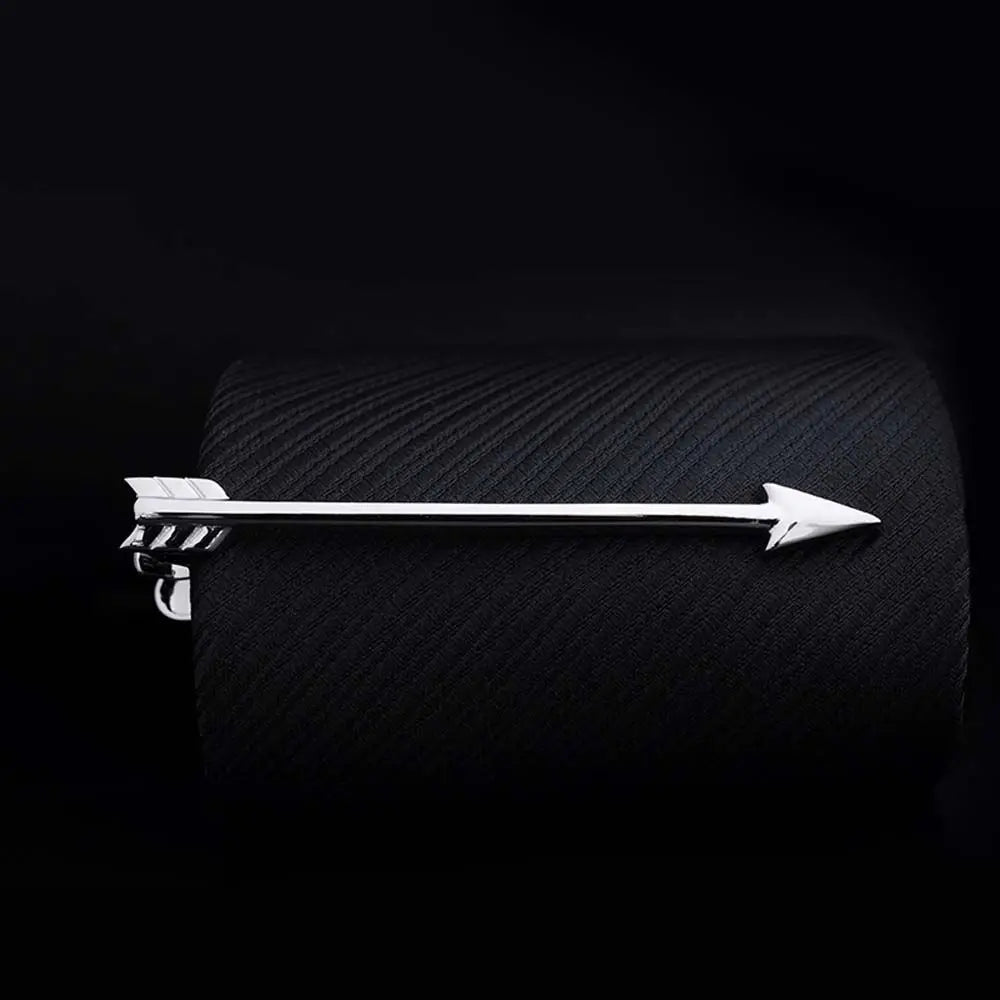 Silver arrow-shaped tie clip on a textured black surface