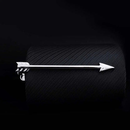 Silver arrow-shaped tie clip on a textured black surface